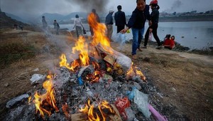 Người dân đốt túi nylon sau khi thả cá trên bờ sông Đà nhằm hạn chế ô nhiễm rác thải nhựa. 