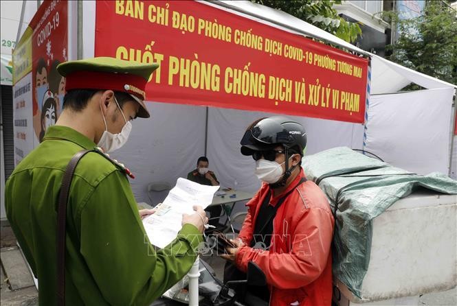 Lực lượng chức năng kiểm tra giấy tờ liên quan người tham gia giao thông tại chốt kiểm soát trên phố Trương Định, quận Hoàng Mai (ảnh chụp sáng 29/7). Ảnh: Trần Việt/TTXVN 