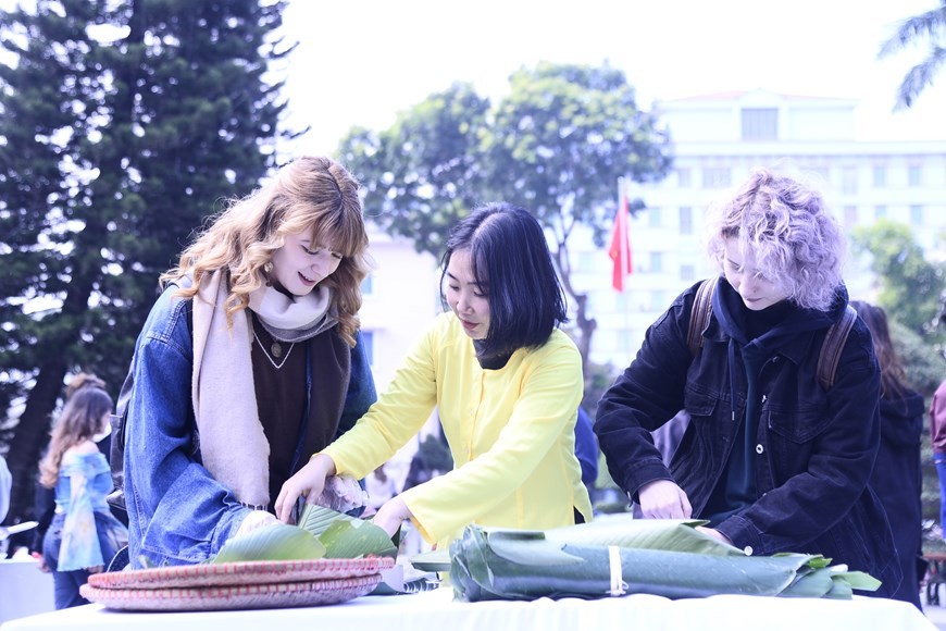 Các sinh viên quốc tế của Trường Đại học Hà Nội thích thú khi được tự tay gói bánh chưng xanh, thức bánh đặc trưng của Tết Nguyên đán cổ truyền. (Ảnh: PV/Vietnam+)