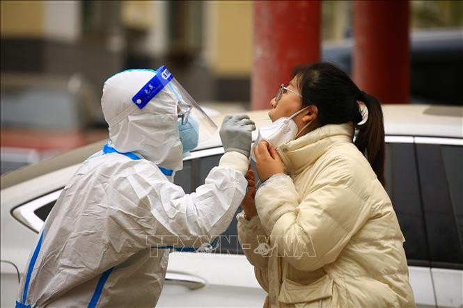 Nhân viên y tế lấy mẫu xét nghiệm COVID-19 cho người dân tại tỉnh Cam Túc, Trung Quốc. Ảnh: AFP/TTXVN