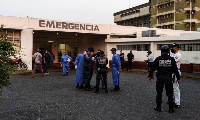 Nhân viên y tế và cảnh sát Venezuela đứng chờ bên ngoài một bệnh viện ở thành phố Guanare, nơi tiếp nhận những người bị thương trong vụ bạo loạn tại nhà tù Llanos ngày 1/5. Ảnh: Reuters