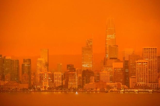 Các tòa cao ốc của San Francisco mờ ảo giữa làn khói mờ màu cam nhìn từ đảo Treasure.