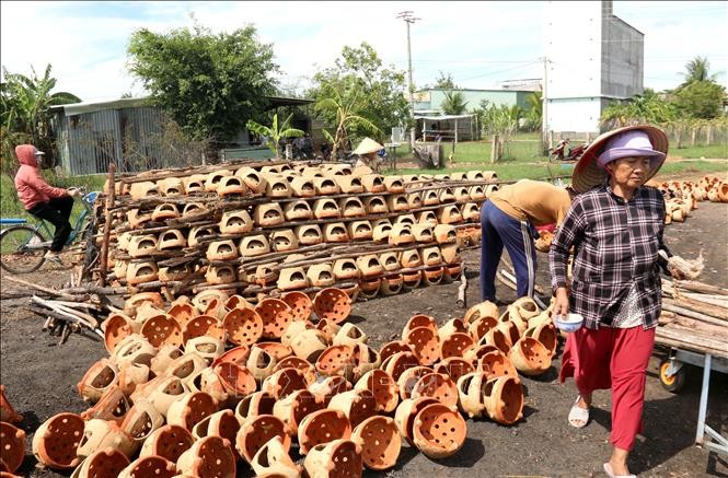 Các sản phẩm gốm được xếp xen kẽ với củi đốt để nung. Ảnh: Nguyễn Thanh/TTXVN