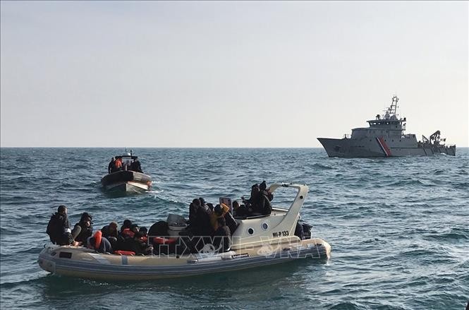 Lực lượng cứu hộ Anh (phía trước) chặn tàu chở người di cư từ Pháp băng qua eo biển Manche. Ảnh tư liệu: AFP/TTXVN