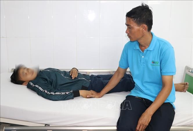 Anh Nguyễn Hữu Tri chăm sóc em Thọ tại Phòng cấp cứu Bệnh viện Sản nhi An Giang sau khi bị nhóm bạn học cùng trường đánh hội đồng.