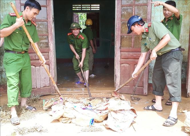 Các chiến sỹ công an huyện Hương Khê chung tay vệ sinh môi trương sau lũ tại xã Hương Đô. Ảnh: Phan Quân/TTXVN