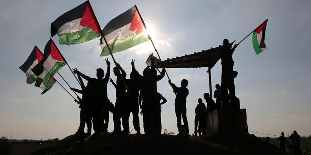 Người dân Palestine giơ quốc kỳ tại khu vực biên giới Israel-Gaza. (Nguồn: AFP)