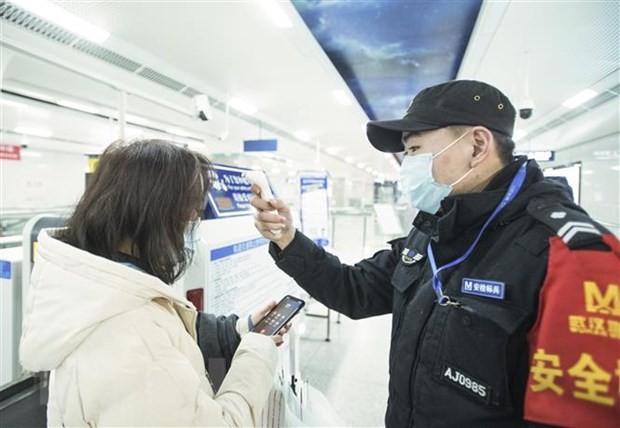 Nhân viên kiểm tra thân nhiệt của hành khách tại một nhà ga ở Vũ Hán, tỉnh Hồ Bắc, Trung Quốc. (Ảnh: THX/TTXVN)