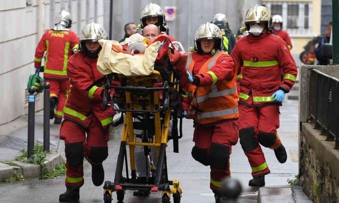 Lính cứu hỏa đưa người bị thương rời hiện trường vụ đâm dao gần văn phòng cũ của tạp chí Charlie Hebdo, ở Paris, Pháp, hôm 25/9. Ảnh: AFP.