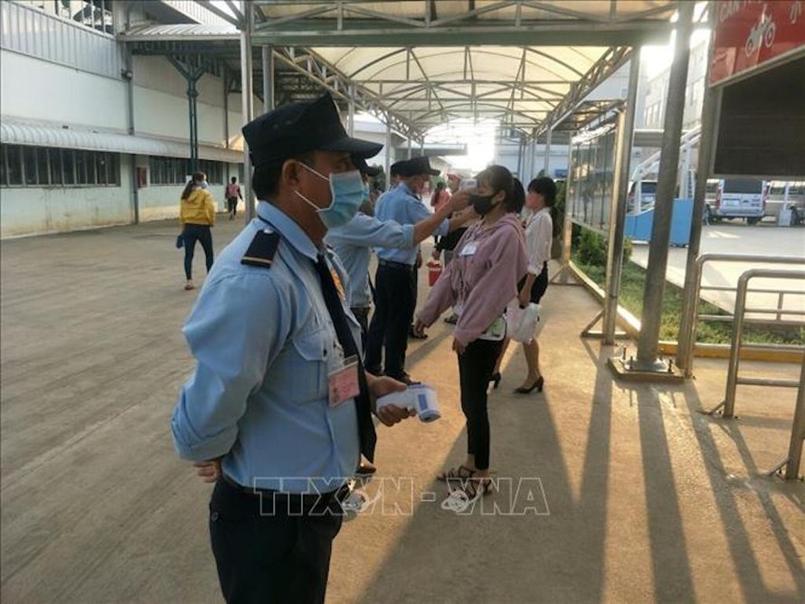 Kiểm tra thân nhiệt cho công nhân trước khi vào ca tại Công ty TNHH Grand Gain tại KCN Đồng Xoài II, tỉnh Bình Phước. Ảnh: Dương Chí Tưởng/TTXVN