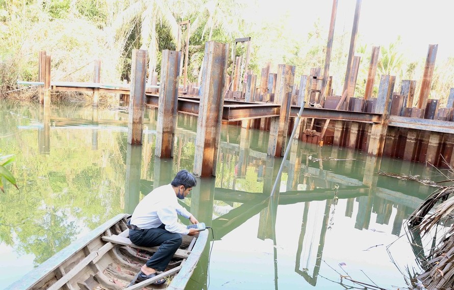 Cán bộ kỹ thuật của Sở Nông nghiệp và Phát triển nông thôn kiểm tra đo độ mặn tại đập ngăn mặn tạm thời trên sông Hàm Luông, xã Đông Sơn, thành phố Bến Tre.