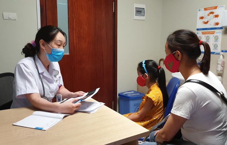 Tiến sỹ Nguyễn Ngọc Khánh khám cho một bé gái dậy thì sớm. (Ảnh: T.G/Vietnam+)