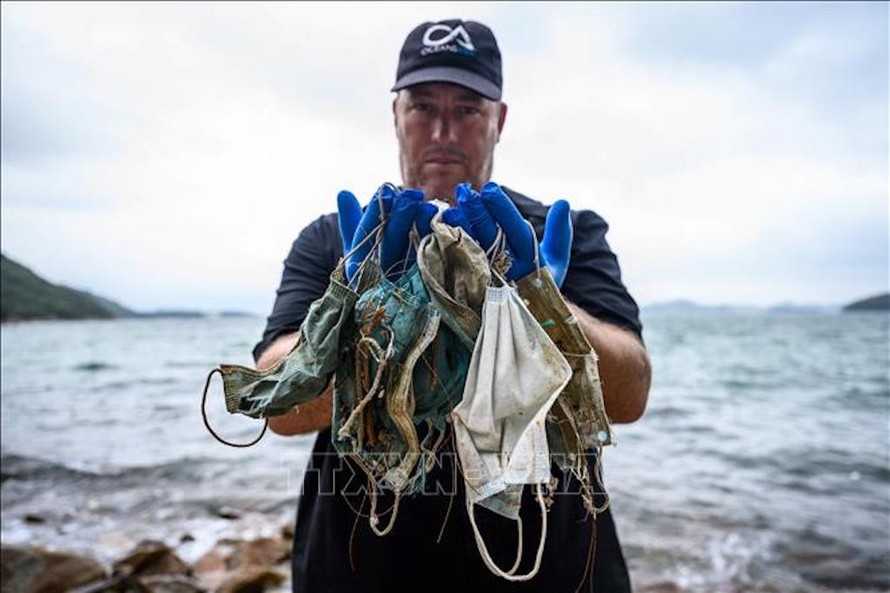 Chuyên gia tổ chức bảo vệ môi trường OceansAsia thu nhặt khẩu trang dùng một lần trên bãi biển vùng đảo Lantau, Hong Kong, Trung Quốc. Ảnh: AFP/TTXVN
