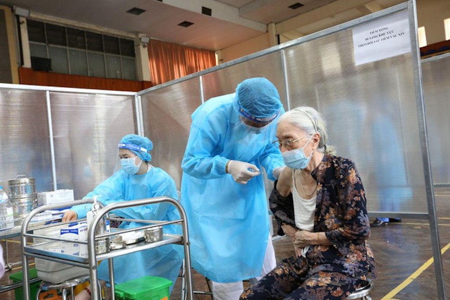 Nhân viên y tế tiêm vaccine phòng COVID-19 cho người cao tuổi tại điểm tiêm bên trong Nhà thi đấu Trịnh Hoài Đức (quận Đống Đa, Hà Nội).