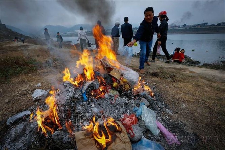 Người dân đốt túi nylon sau khi thả cá trên bờ sông Đà nhằm hạn chế ô nhiễm rác thải nhựa. 