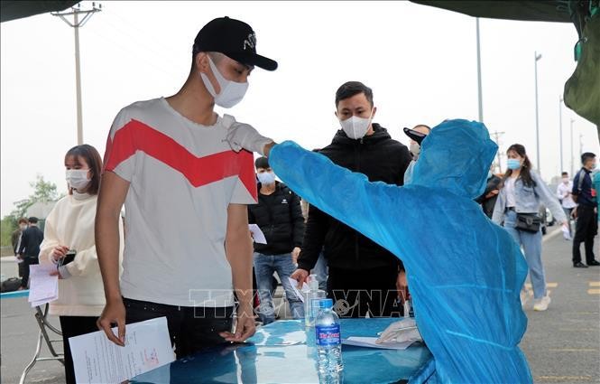 Những người rời Quảng Ninh về quê ăn Tết thực hiện đo thân nhiệt tại trạm kiểm soát dịch bệnh COVID-19 cầu Bạch Đằng (huyện Quảng Yên). (Ảnh minh họa: TTXVN)