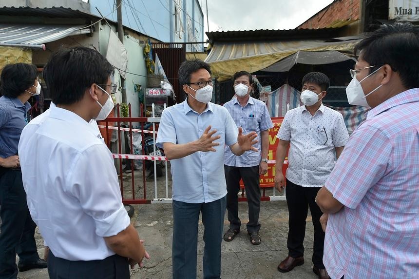 Phó thủ tướng Vũ Đức Đam trao đổi với lãnh đạo quận Bình Tân (TP.HCM) trước một khu nhà trọ công nhân đang bị phong toả, chiều 25/7. Ảnh: VGP.