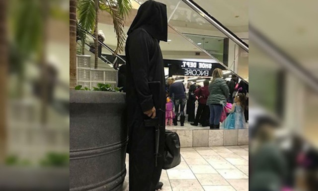 Người đàn ông Mỹ mặc trang phục đen có mũ trùm đầu, hai tay cầm túi và súng trường giả ở trung tâm thương mại bang Nebraska. Ảnh: Twitter.