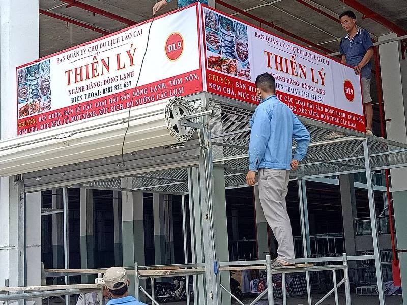 Tiểu thương lắp đặt biển bảng chuẩn bị kinh doanh tại chợ du lịch Lào Cai