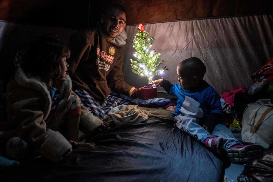 Gia đình anh Aguilar Duarte đến từ Honduras chụp ảnh với cây thông Giáng sinh trong lều của họ tại một trạm trú ẩn tạm thời ở trung tâm thành phố Tijuana.