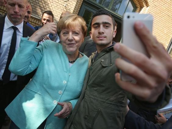 Anas Modamani chụp hình chung với bà Merkel. Ảnh: Independent