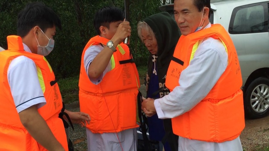 Các cán bộ y tế huyện Phú Vang vào vùng lũ đón bệnh nhân hơn 80 tuổi bị cao huyết áp do trạm y tế xã chuyển lên. (Ảnh Vân Triều)