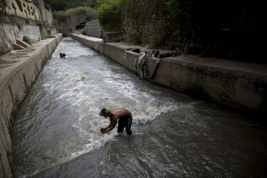 Mỗi ngày, dòng sông Guaire đều xuất hiện những người mò rác đê rkieems tiền sống qua ngày. (Nguồn: AP)