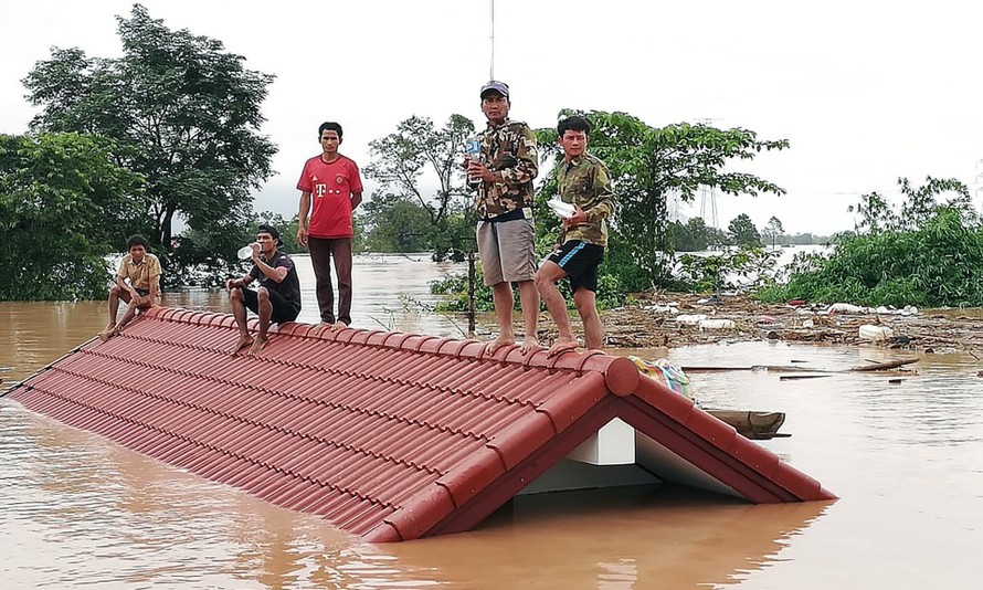 Nhiều dân làng đứng trên nóc nhà để tránh nước lũ từ vụ vỡ đập thủy điện. (Nguồn: EPA).