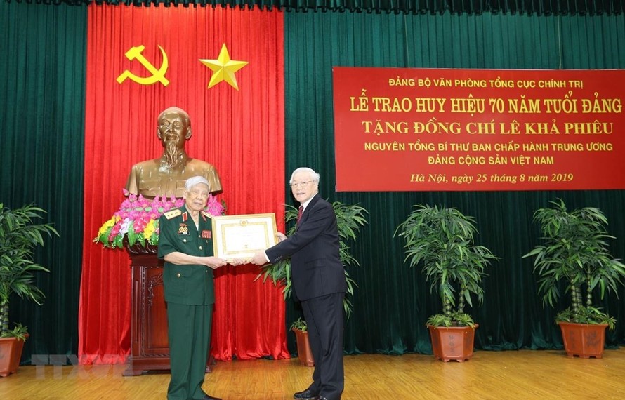 Tổng Bí thư, Chủ tịch nước Nguyễn Phú Trọng, Bí thư Quân ủy Trung ương trao Huy hiệu 70 năm tuổi Đảng tặng đồng chí Lê Khả Phiêu. (Ảnh: Trí Dũng/TTXVN))