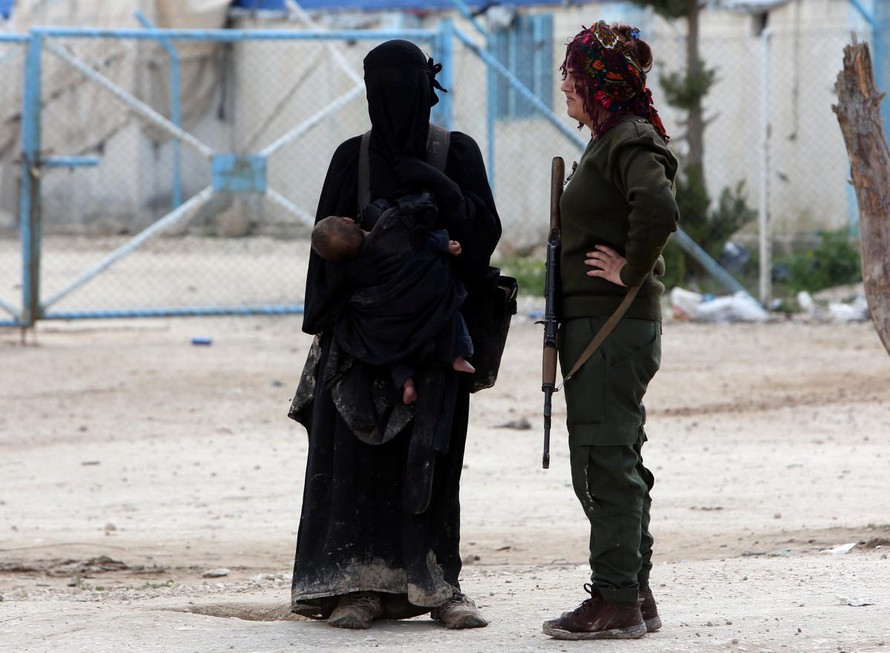 Một thành viên SDF đứng cạnh vợ một tay súng IS ở trại al Hol ở Syria. Ảnh: Reuters