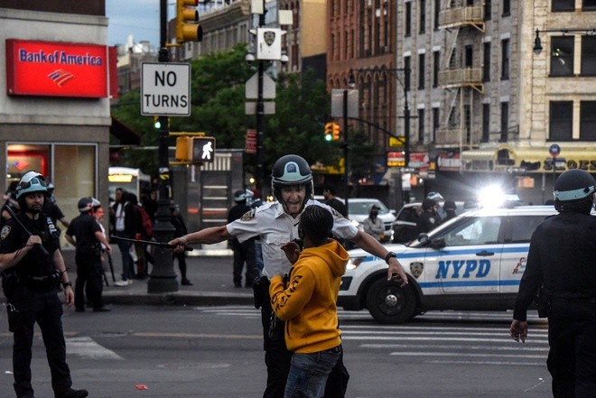 Cảnh sát yêu cầu một thiếu niên tuân thủ lệnh giới nghiêm sau 20h ở khu Bronx, New York. Ảnh: New York Times.
