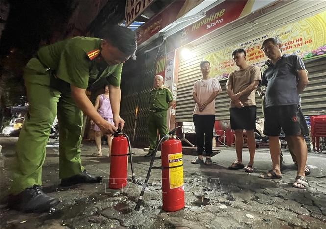 Tổ liên gia số 05, phường Bưởi, quận Tây Hồ nghe cán bộ công an hướng dẫn cách sử dụng bình chữa cháy. Ảnh: Lâm Khánh - TTXVN