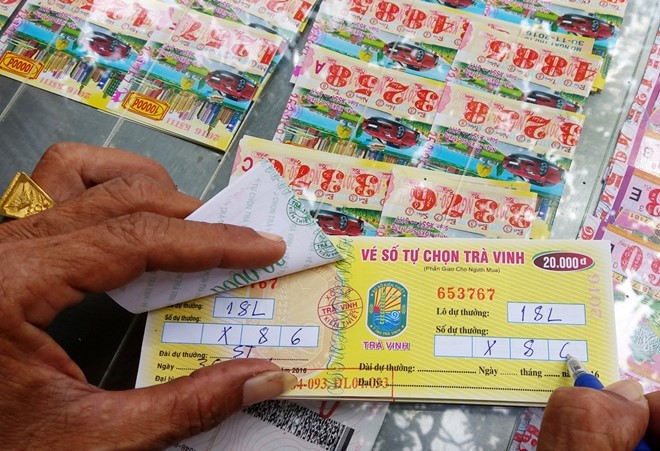 Một người đến điểm vé số tự chọn ở tỉnh Trà Vinh mua "số đề" bao 18 lô. Anh này chọn 2 số cuối 86 để dò kết quả mở thưởng chiều 30/11 của Công ty XSKT Sóc Trăng. Ảnh: Việt Tường.