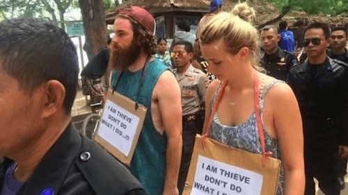 Cặp đôi phải diễu hành trong sự xấu hổ với tấm biển ghi dòng chữ: “Tôi là kẻ ăn cắp. Xin đừng làm như tôi”. Ảnh: SCMP.