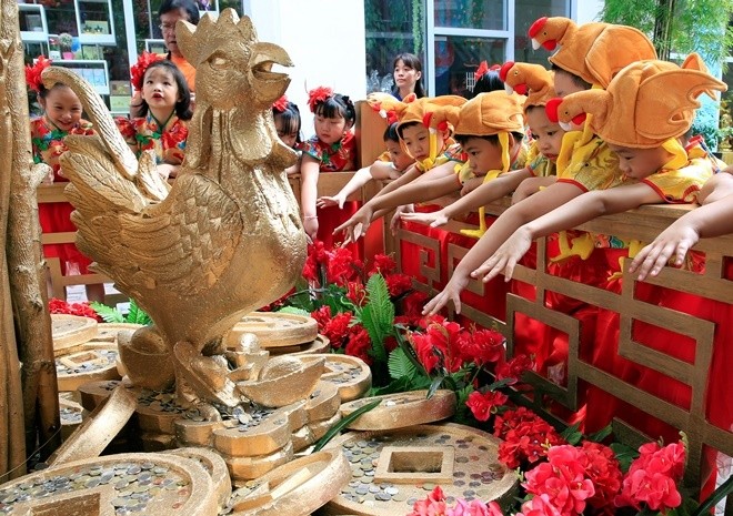 Các học sinh Philippines gốc Hoa đội mũ gà trống và ném đồng xu vào nơi đặt tượng gà màu vàng để cầu may mắn, thịnh vượng tại trung tâm mua sắm Lucky Chinatown, thành phố Binondo, Philippines. 