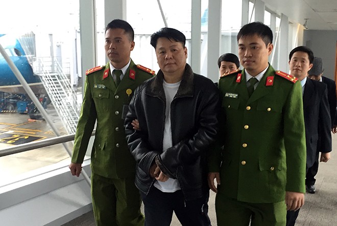 Lực lượng Công an Việt Nam dẫn giải tội phạm truy nã Nguyễn Xuân Đại (mặc áo đen ở giữa hàng đầu ảnh) tại sân bay quốc tế Nội Bài.