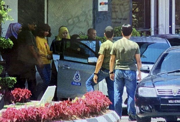 Siti Aishah (áo vàng) được hộ tống vào xe cảnh sát hôm 16/2. Ảnh: The Star.
