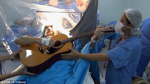 Rolden Batista say sưa chơi ghita và hát dân ca, trong khi các bác sĩ tập trung chuyên môn của mình. Ảnh: CEN/A Tribuna.
