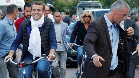Tổng thống Pháp Emmanuel Macron (trái) cùng phu nhân Brigitte Trogneux (giữa) đạp xe rời nhà riêng ngày 10/6 ở Le Touquet trong dịp về đây nghỉ cuối tuần và đi bỏ phiếu Quốc hội - Ảnh: Reuters