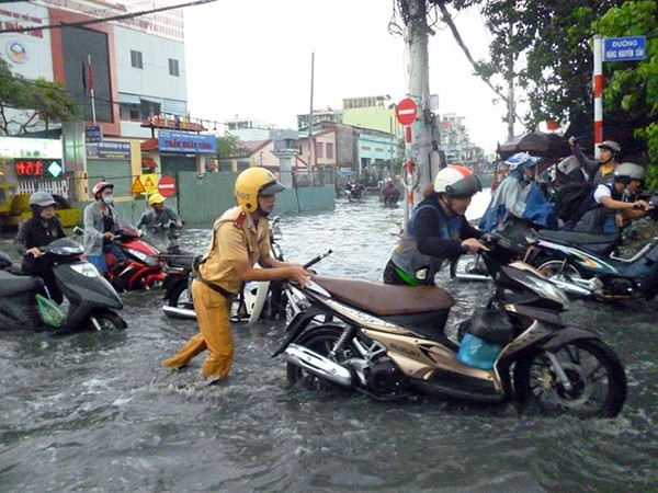 Một CSGT đẩy xe giúp người dân qua đoạn đường ngập nước (Ảnh: CAND).