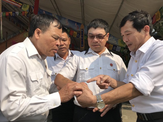 Đồng đội xem lại vết thương trên tay cựu chiến binh Nguyễn Văn Thống. Ảnh: Tuổi Trẻ