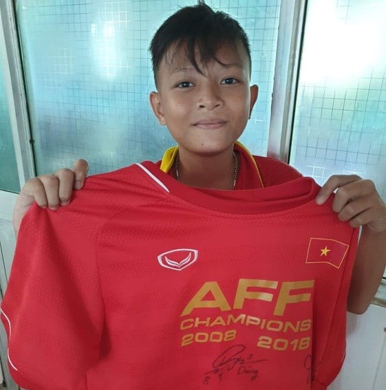 Hoàng Long cầm áo đấu có các chữ ký của tuyển thủ ĐT Việt Nam. Ảnh: Facebook