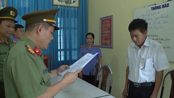 Ông Trần Xuân Yến, Phó Giám đốc Sở GD&ĐT tỉnh Sơn La (áo trắng), nghe tống đạt quyết định khởi tố bị can. Ảnh: Tuổi Trẻ