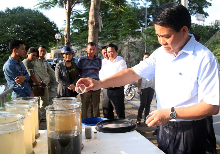 Chủ tịch Nguyễn Đức Chung kiểm tra các mẫu nước. Ảnh: VnExpress