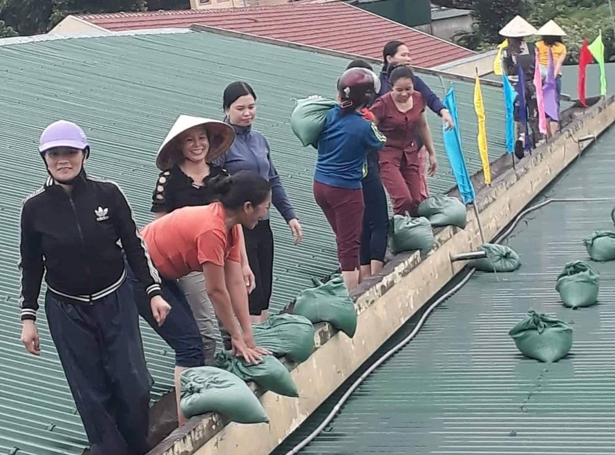 Các cô giáo mầm non vác bao cát lên mái nhà để gia cố trước thềm bão số 4 đổ bộ. Ảnh: VietNamNet