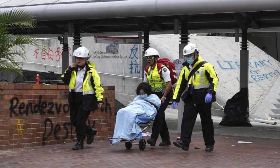 Một người biểu tình được nhân viên y tế hộ tống ra khỏi trường Đại học Hong Kong. Ảnh: The Guardian