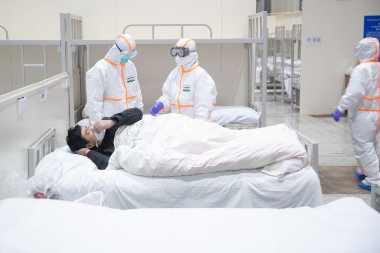 Nhân viên y tế khám cho bệnh nhân bị nhiễm nCoV tại bệnh viện dã chiến ở Trung tâm Triển lãm và Hội nghị Quốc tế Vũ Hán. Ảnh: EPA