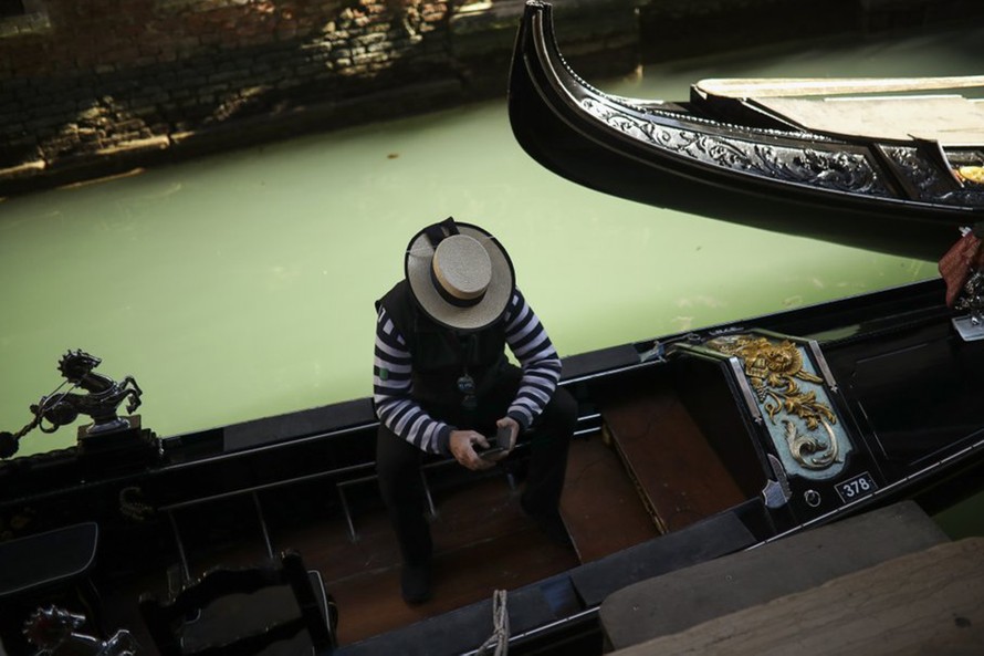 Một người trèo thuyền gondola ngồi đợi khách tại Venice. Ảnh: AP