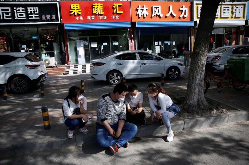 Đầu bếp Zhang Jianpeng, cùng vợ và hai lao động nhập cư khác ngồi bên ngoài một cơ quan tuyển dụng ở ngoại ô Bắc Kinh. Ảnh: Reuters