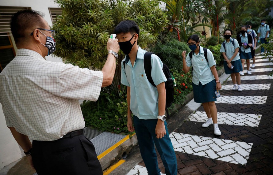 Học sinh Singapore kiểm tra thân nhiệt trước khi vào lớp. Ảnh: Reuters